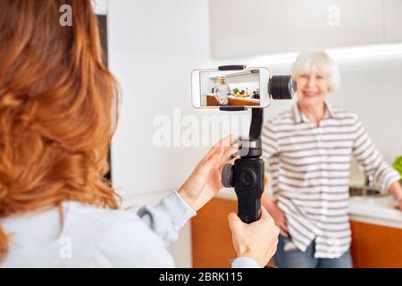 Mature aged woman and her daughter using modern smartphone, recording online video Stock Photo