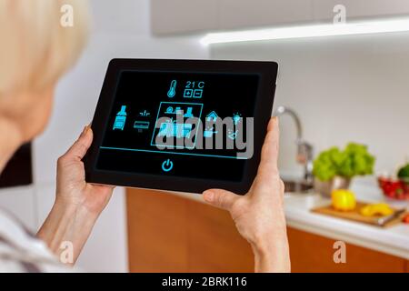 Grey hair woman using modern tablet computer with smart house app Stock Photo