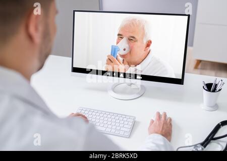 Doctor In Video Conference Call With Senior Patient Using Oxygen Nebulizer Stock Photo