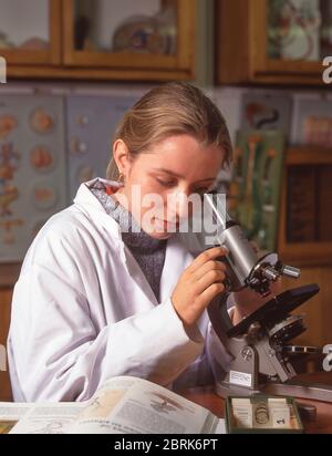 Female student using microscope in class, Surrey, England, United Kingdom Stock Photo