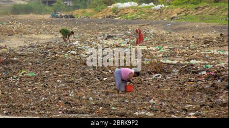 Sea Pollution: Garbage dumped in the Sri Lankan Sea near Colombo. women collects plastic things in a pile of garbage brought by the surf from the sea Stock Photo