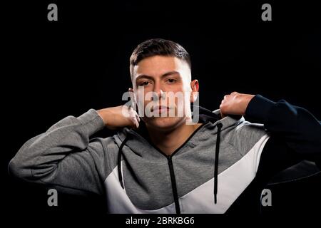 Young casual man wearing tracksuit standing over black background Stock Photo