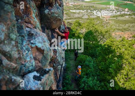 Man is engaged in sports rock-climbing. The climber climbs the rock. Outdoor activities Stock Photo