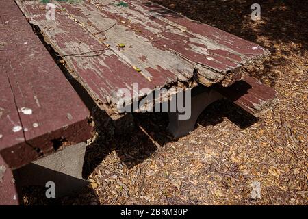 aged rough weathered picnic table in park on mulch with peeling paint Stock Photo