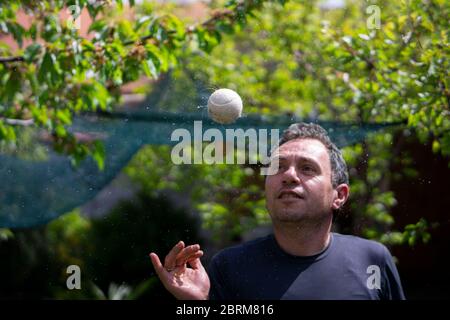 Man in his forties throws and spins a ball that makes water spirals on a green background Stock Photo