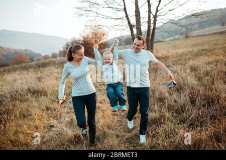 Parents on country walk and lifting son. Mother and father holding son's hands holding him mid air. Stock Photo