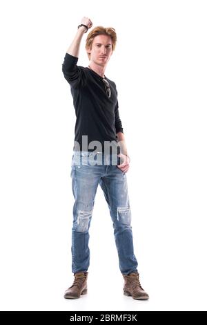 Achievement concept. Young handsome red hair man with raised hand shaking clenched fist success sign. Full body length isolated on white background.