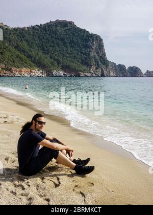 Young man sitting by the cleopatra beach and relaxing Stock Photo