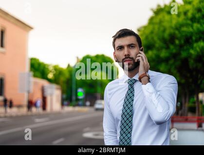 Young business man with white shirt and tie in outdoor city making a phone call Stock Photo