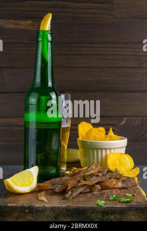 Dried carp fish sticks with beer, lemon and potato chips on dark wooden board. Snack on fish with beer. Close-up Stock Photo