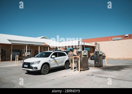 Denham, Nov 2019: Man tourist filling up rented car with petrol at gas station. Refueling a car with gasoline at self service petrol station Stock Photo