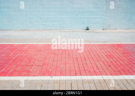 Sidewalk with a red painted bike path and white wall, nobody and single space. Stock Photo