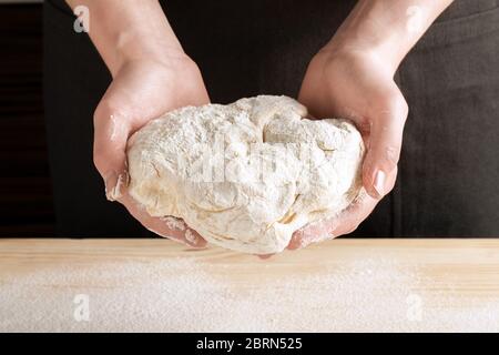 Front view of females hands hold the dough for baking pizza, bread, cakes or pies. Step-by-step recipe for cooking ravioli or dumplings, step 5. Stock Photo