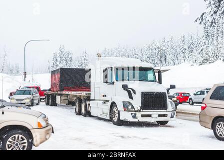 white truck on snow road with traffic jam on snowy day in winter. Stock Photo