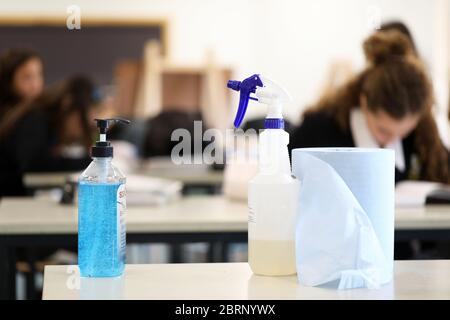 Deliberately blurred students in the background working on classwork. Hand sanitizer sanitiser pump with disinfectant spray bottle in the foreground. Stock Photo