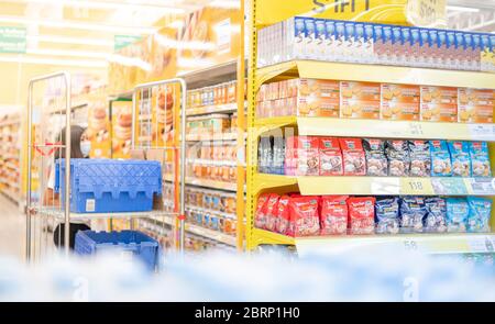 BANGKOK / THAILAND: MAY 15 - 2020: The employer wear surgical mask and uniform counting the carton of food at the supermarket aisle prepare to shopper Stock Photo