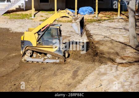Mini bulldozer construction of yellow color on the earth moving scoop excavator Stock Photo