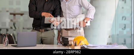 Cropped shot of two engineers working together with digital tablet, laptop and office supplies in meeting room Stock Photo