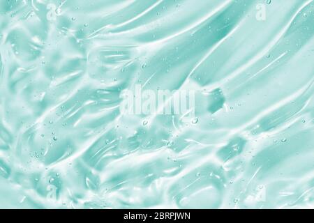 Hand sanitizer, alcohol gel, beauty serum background. Skin care clear liquid cream splash. Blue green transparent cosmetic product texture closeup Stock Photo