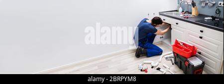 Plumber Fixing Kitchen Pipes. Water Sink Service Stock Photo
