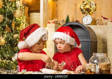 Cute kids in santa hats preparation holiday dinner for family. Santa cook. Cookie on Christmas Eve as a thank Santa gift for leaving presents to a gra Stock Photo