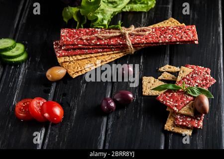 Beetroot and rye flour crackers with vegetables for making snacks on a black background. Vegetarianism and healthy eating. Stock Photo