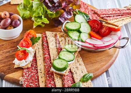 Beetroot and rye flour crackers with vegetables for making snacks on a wooden background. Vegetarianism and healthy eating. Stock Photo