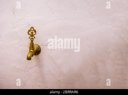 Antique bronze faucet on a white wall. Stock Photo