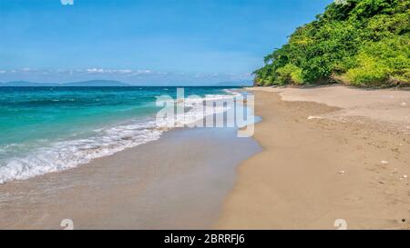 A beautiful deserted beach, as an ebb tide leaves wet sand on the north side of Mindoro Island near Abra de Ilog, Philippines. Stock Photo