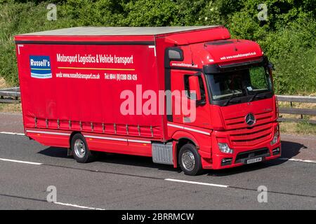 Russells Transport - Motorsport Logistics and Race Car Transport & Vehicle Transport; Haulage delivery trucks, red lorry, transportation, truck, cargo carrier, Mercedes Benz vehicle, European commercial transport, industry, M6 at Manchester, UK Stock Photo