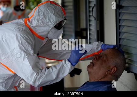 Medical workers wearing special suits to protect against coronavirus, conduct testing for COVID-19 at elderly home. Stock Photo