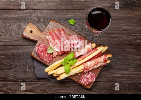 Various meat antipasto. Appetizer selection board and glass with red wine. Top view. Flat lay Stock Photo