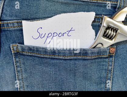 Concept of mechanical business. Blue jeans pocket with a piece of paper with the text support written by hand and a key. Stock Photo