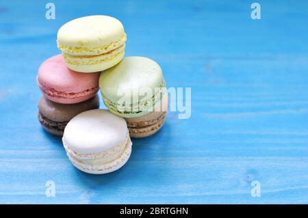 Pile of colorful macarons on blue background. Close up, copy text. Stock Photo