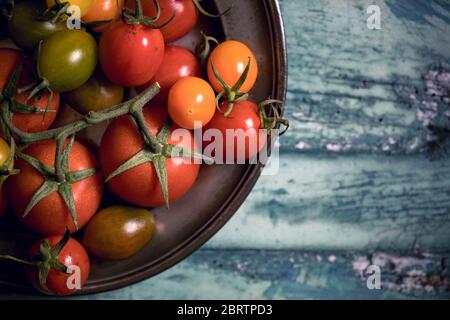 Colourful tomatoes on a pewter plate over old, painted wood background Stock Photo