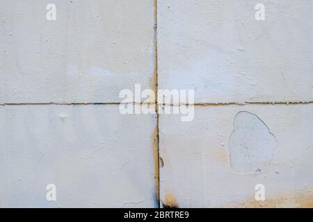 Light gray paint peels off the surface of an old metal sheet. On the bottom layer peach-colored paint is exposed. Grunge pattern. Stock Photo