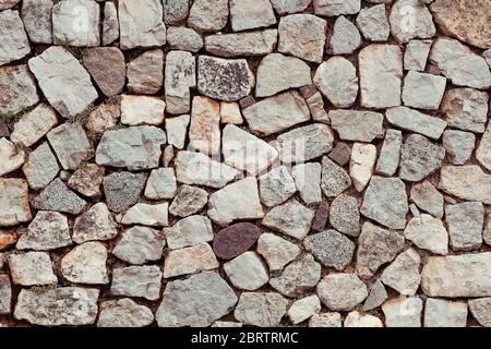 Rustic vintage wall of uneven marble granite porphyry stones italian style Stock Photo