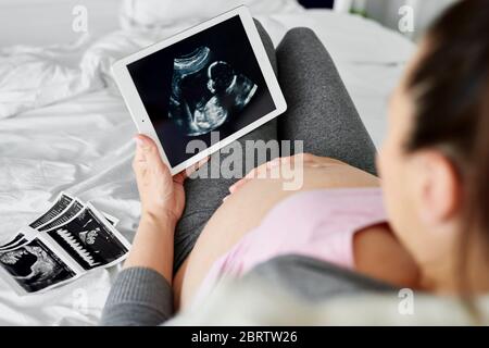 Rear view of pregnant woman browsing ultrasound image on tablet Stock Photo