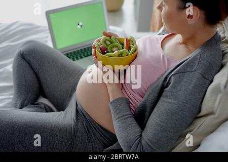 Pregnant woman relaxing in front of computer Stock Photo