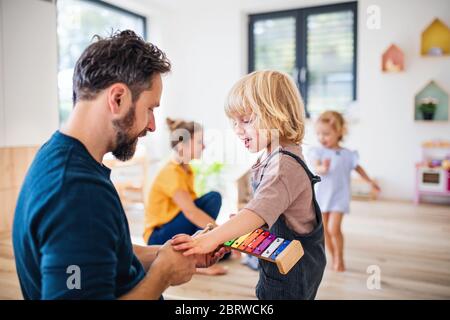 Young family with two small children indoors in bedroom playing. Stock Photo