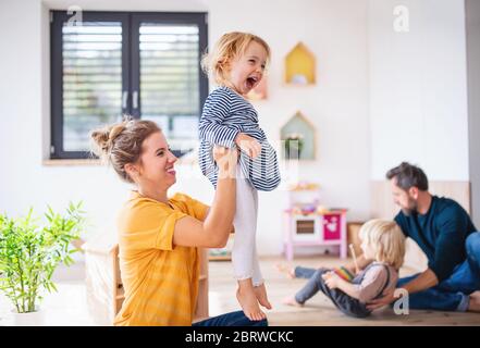 Young family with two small children indoors in bedroom having fun. Stock Photo