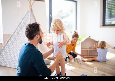 Young family with two small children indoors in bedroom playing. Stock Photo
