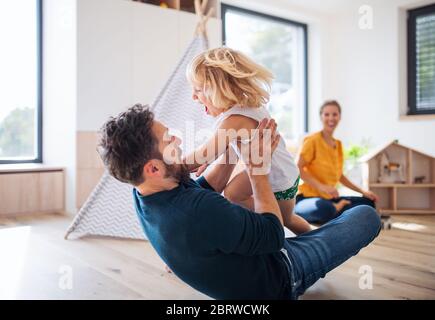 Young family with small child indoors in bedroom having fun.