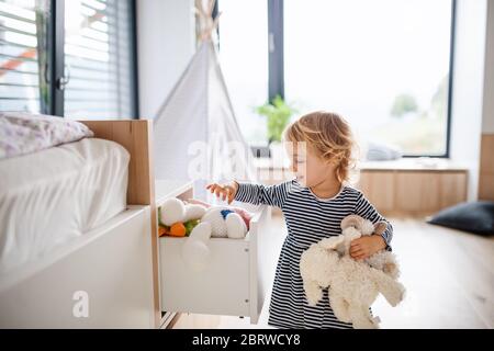 Cute small toddler girl indoors in bedroom playing. Stock Photo