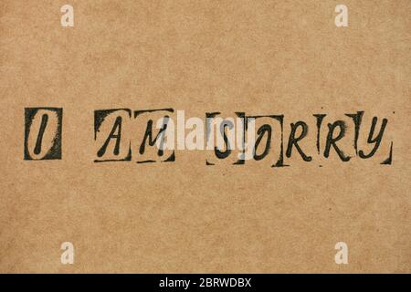 Words I am Sorry made by black alphabet stamps on Cardboard. Stock Photo