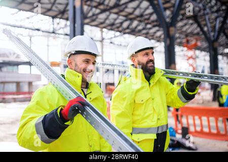 Men workers walking outdoors on construction site, working. Stock Photo