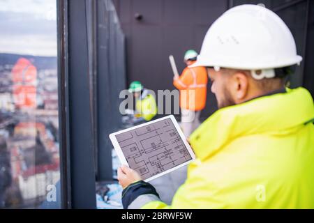 Man engineer standing on construction site, holding tablet. Stock Photo