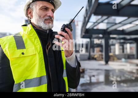 Man engineer using walkie talkie on construction site. Stock Photo