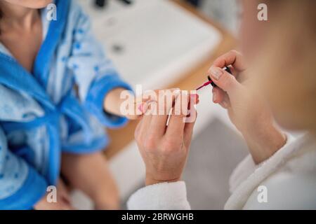 Midsection of mother painting nails of small daughter indoors at home. Stock Photo