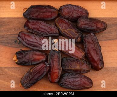 Heap of organic pitted dates isolated on wooden, top view Stock Photo